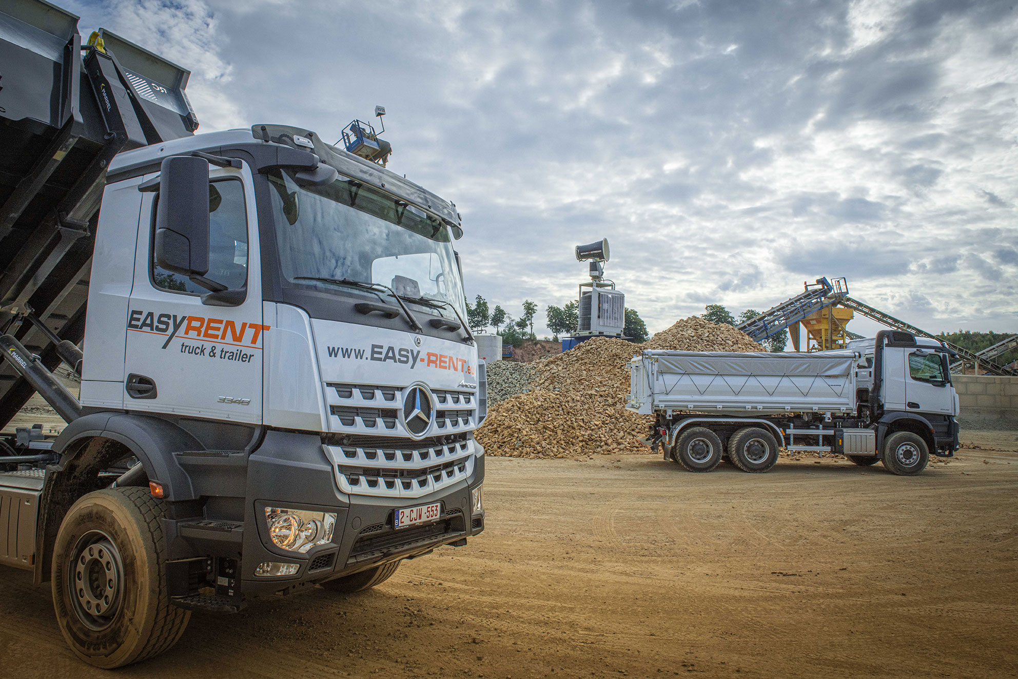 LKW auf Baustelle mit Mercedes-Benz Abrollkipper im Vordergrund und 3-Achskipper im Hintergrund