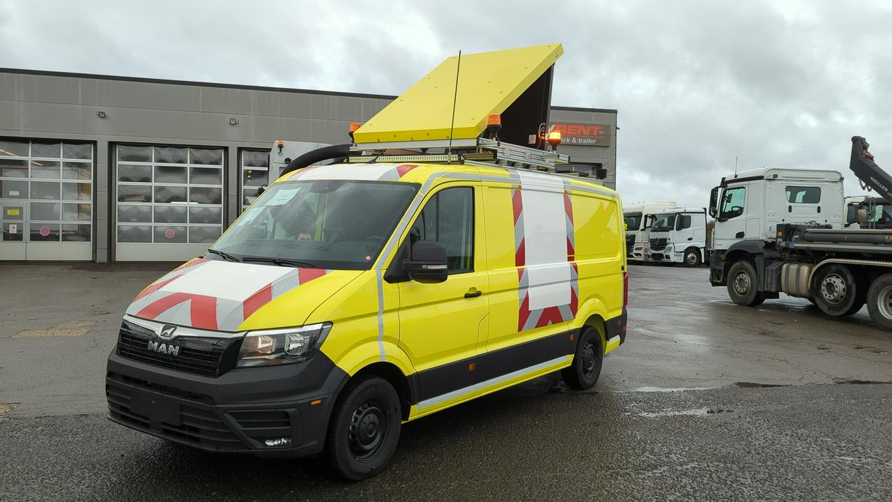 Gelbes Begleitfahrzeug mit Beschriftung und Warntafel auf dem Parkplatz