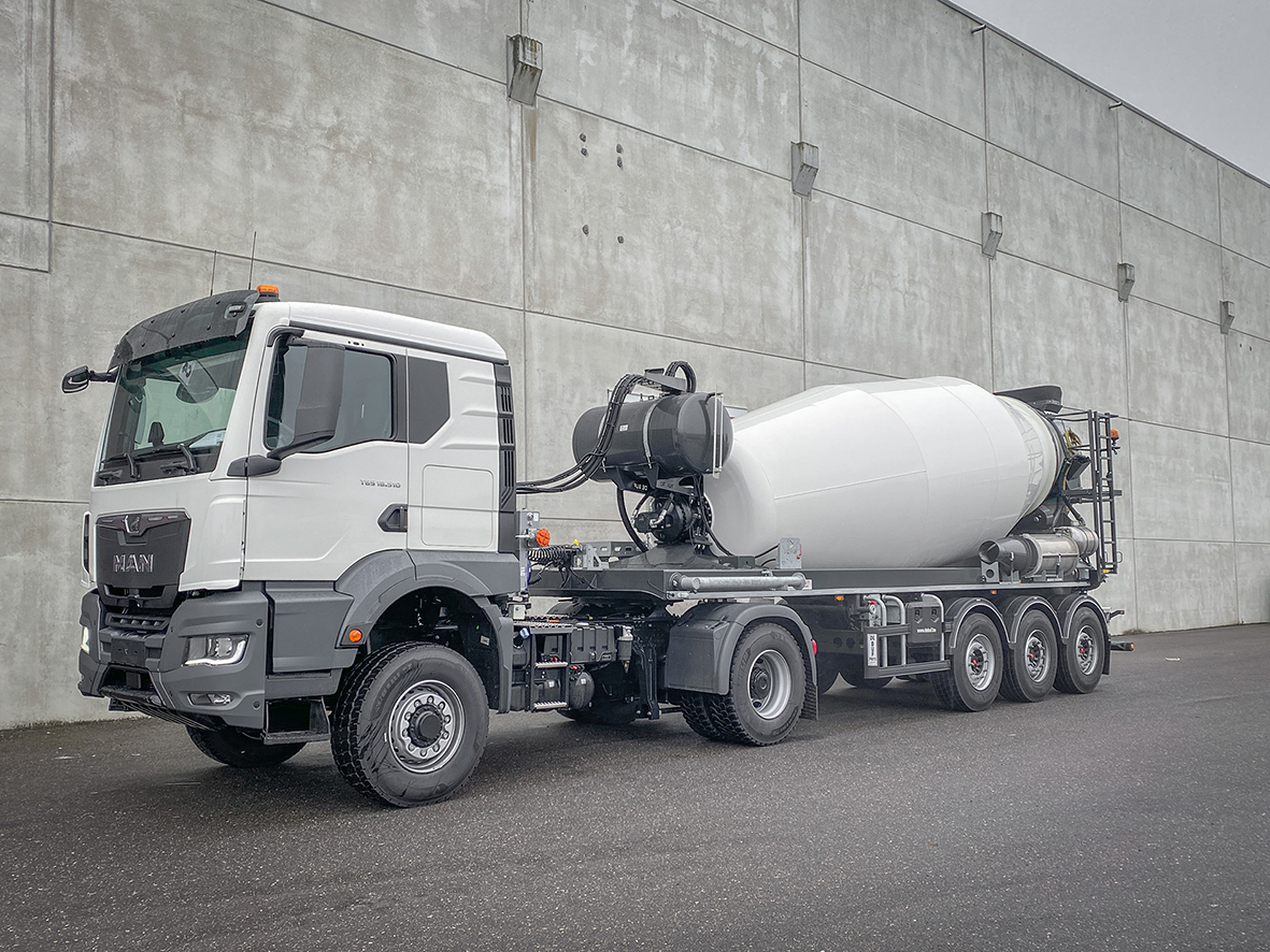 Tracteur MAN avec semi-remorque bétonnière De Buf devant un mur gris