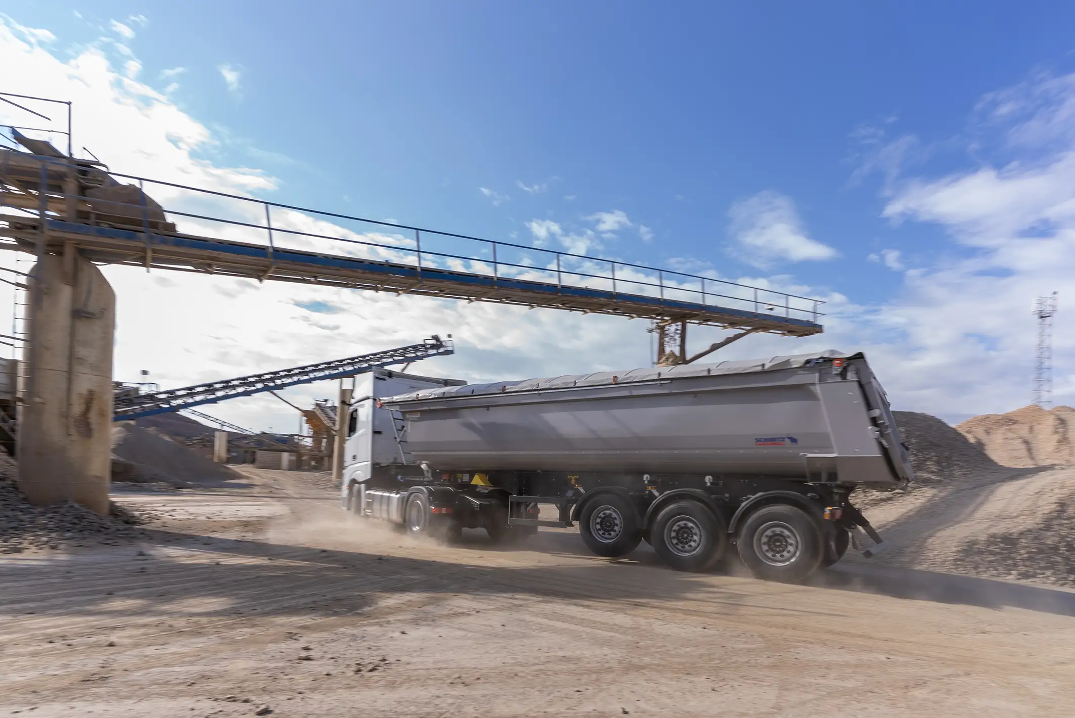 Sattelzug 3-Achs Stahlkipper Schmitz Cargobull fährt auf einer Baustelle
