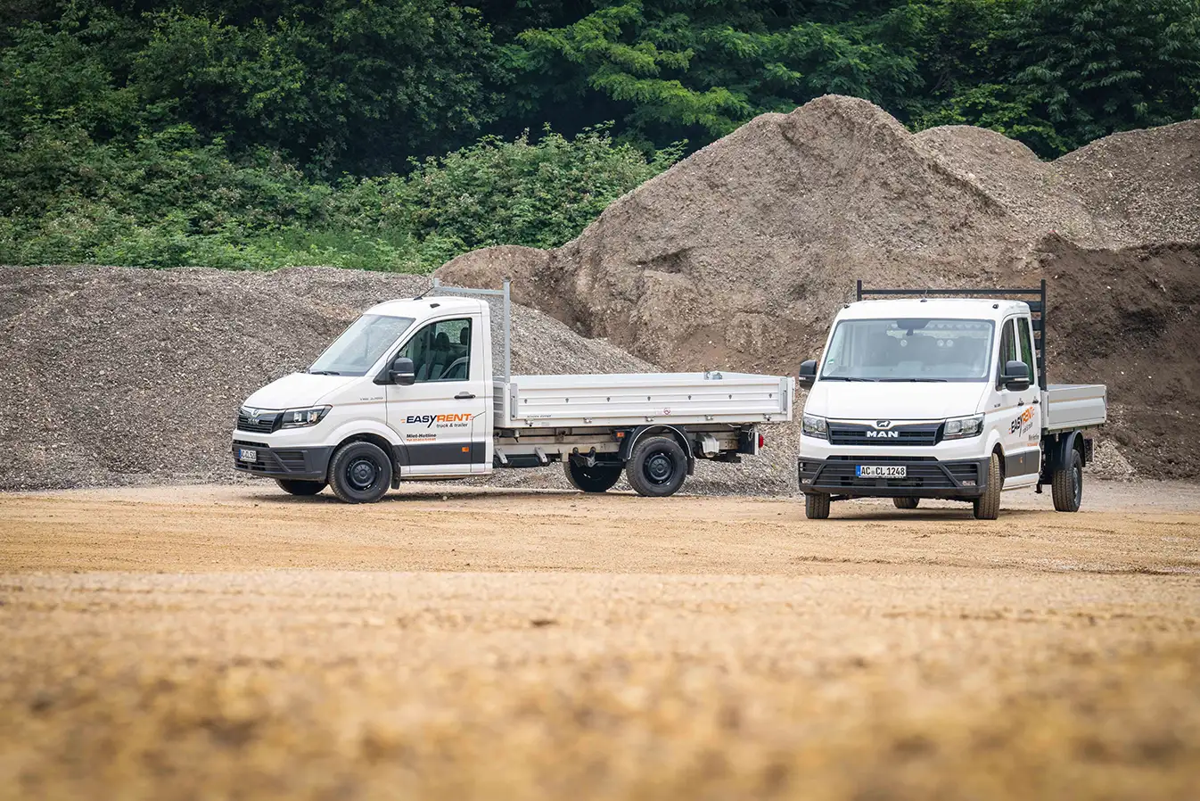 Two white MAN TGE 4x2 vans with Easy Rent lettering. One with a flatbed and a three-way tipper.