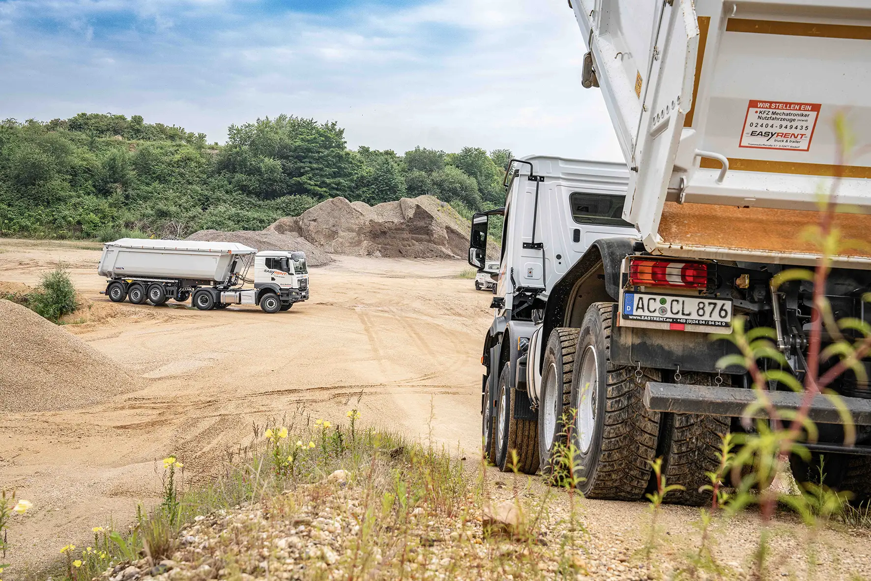 Aufnahme einer Baustelle. Im Vordergrund rechts ein 8x4 Kipper LKW. Im Hintergrund eine Easy Rent trruck & trailer Sattelzugmaschine mit einem Schmitz Cargobull 3-Achs Stahlkipper